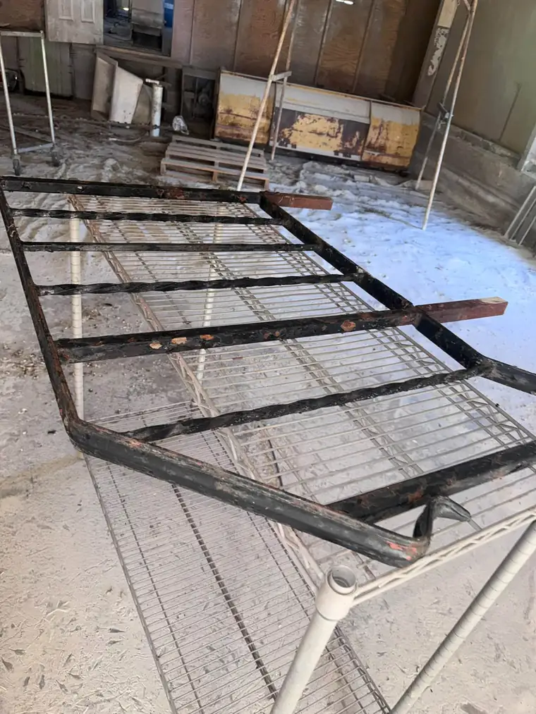 Rusty black steel frame end with failing paint before blasting