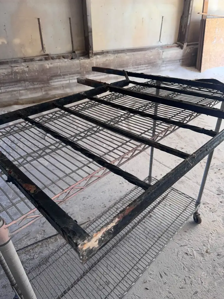 Black steel rack frame with rust and failing paint before sandblasting